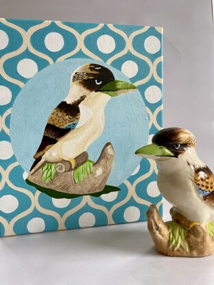 A kookaburra figurine set on a blue beige and white patterned background 