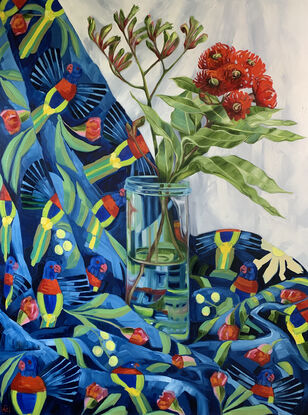 Red gum blossom in a tall glass vase on Lorikeet patterned fabric in bright blues and reds