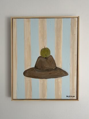 Green apple sitting on top of cowboy hat