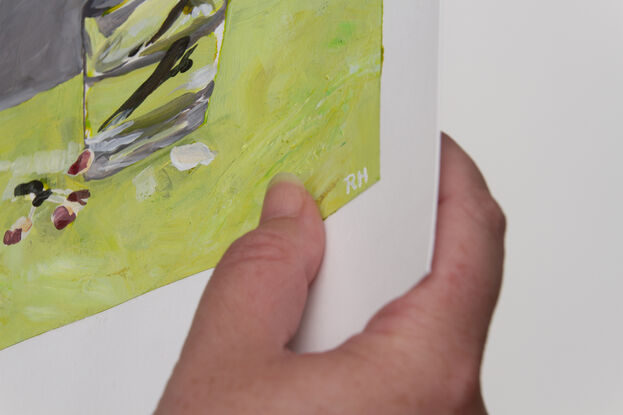 This is a single cherry blossom, in a glass of water, painted on a bench of bright green, with a grey backdrop.