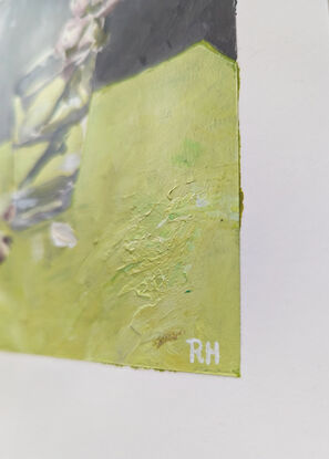 This is a single cherry blossom, in a glass of water, painted on a bench of bright green, with a grey backdrop.