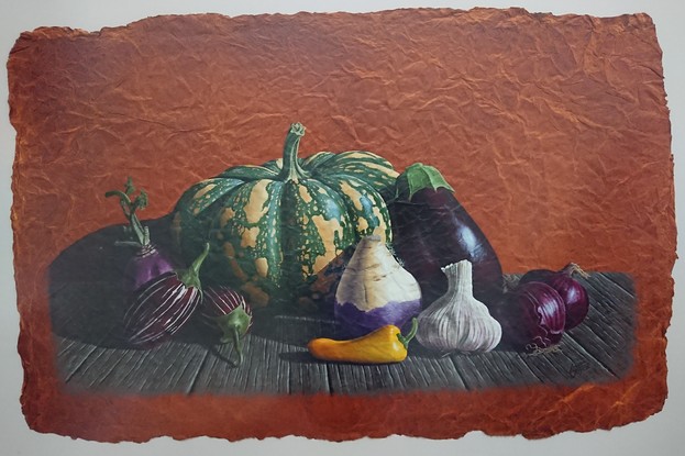 A large striped pumpkin surrounded by a variety of purple vegetables sitting on an old timber bench.