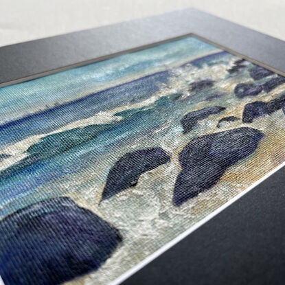 Turquoise ocean waves crashing onto rocks before flowing into sandy beach tidepools.