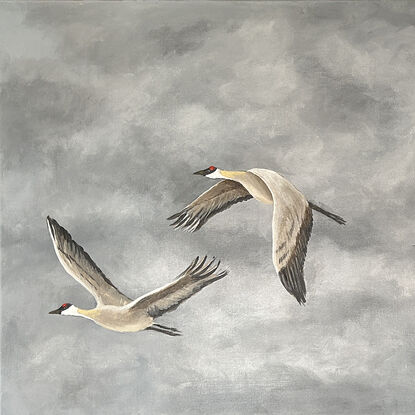 A small flock of cranes flying across a cloudy sky.