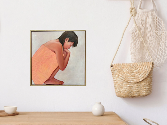 A young woman crouching, looking down with her arms wrapped around her knees.