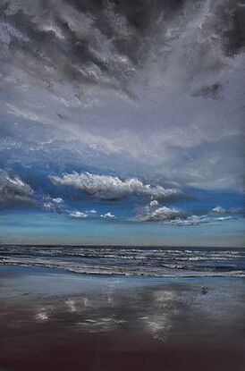 A dynamic day in the beach with waves and a stormy sky with reflections in the sand 