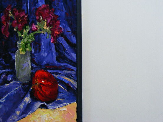 Red flowers in a small vase and a red apple 