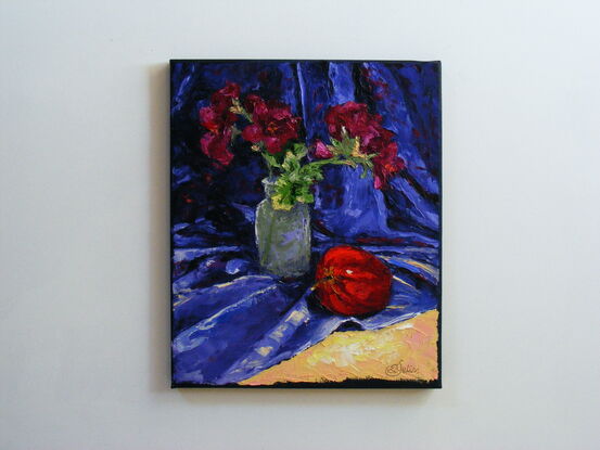 Red flowers in a small vase and a red apple 