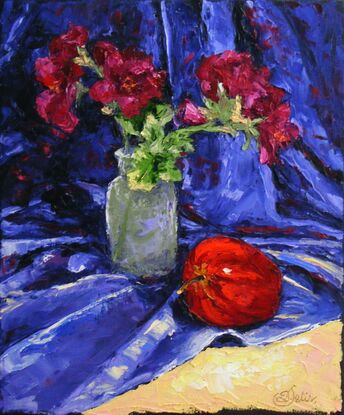 Red flowers in a small vase and a red apple 