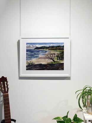 A watercolour painting made in a modern style captures the vastness of a surf beach on North Stradbroke Island, Queensland. The artist made the painting while on location in a method referred to as 'en plein air'. This method grants the painting a fresh and expressive look that suits the subject of wild weather rolling in from the sea. The beach is a beige expanse with lavender shadows falling across it from the large thunderheads above. The wind swept form of a dark skeletal tree in the foreground hints at the danger posed by weather on the island and is formally linked, via shared tonal value, to the mass of stone the artist has depicted in the foreground. This stone implies that she was sitting atop the rock formation as she worked on the piece.