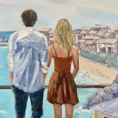 A young couple looking out to sea. He with dark hair, wearing  a white linen shirt. She with blonde hair and a warm brown dress.