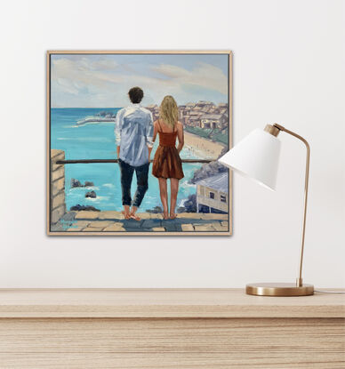 A young couple looking out to sea. He with dark hair, wearing  a white linen shirt. She with blonde hair and a warm brown dress.