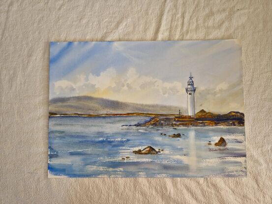 A lighthouse seascape with a backdrop of mountains.