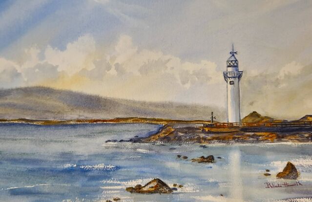 A lighthouse seascape with a backdrop of mountains.