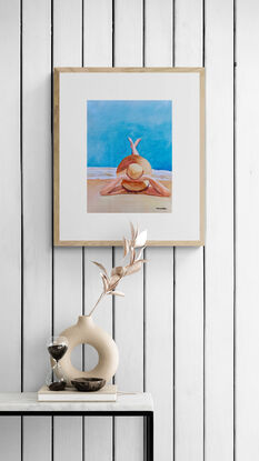 artwork showing a woman with a large sun hat lazing on the beach with her legs stretched out enjoying the sun
