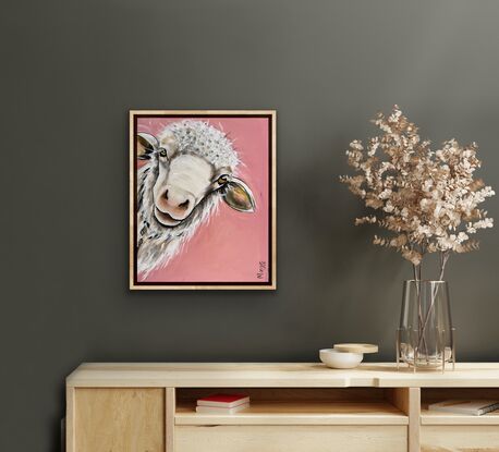 A young sheep with an inquisition expression staring out from the canvas with a peach pink background.