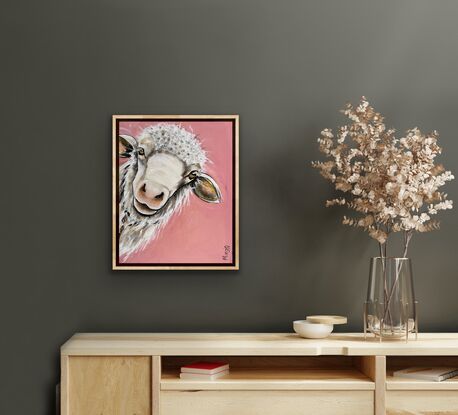 A young sheep with an inquisition expression staring out from the canvas with a peach pink background.