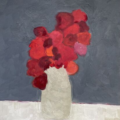 Red flowers in tall neutral vase