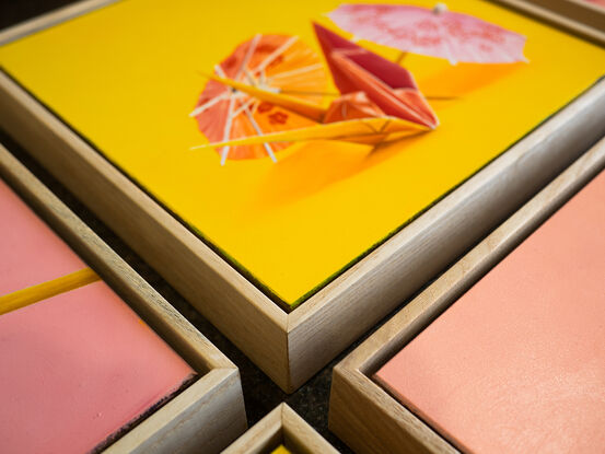 An origami bunny standing amongst cocktail parasols against a yellow background