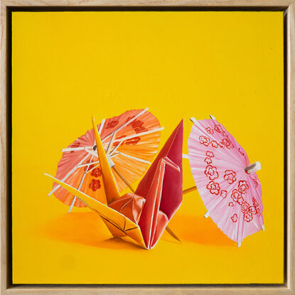 An origami bunny standing amongst cocktail parasols against a yellow background