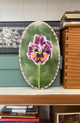 Little purple and yellow pansy flower framed by an antique/vintage vibe pink frame set against a soft green background