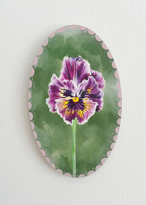 Little purple and yellow pansy flower framed by an antique/vintage vibe pink frame set against a soft green background