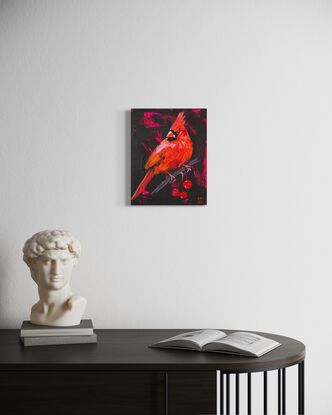 Small painting on wood panel of red cardinal bird perched on a branch with cherry like fruit against a black background