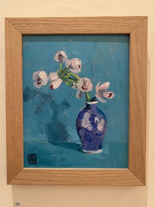 Pale pink orchids in blue vase.