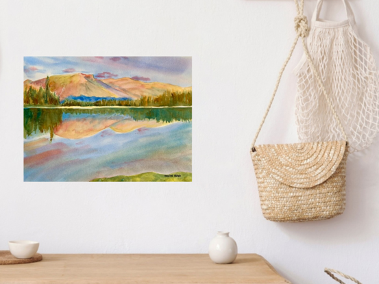 artwork showing a sunny day landscape vista with distant fells and a mirror lake reflection
