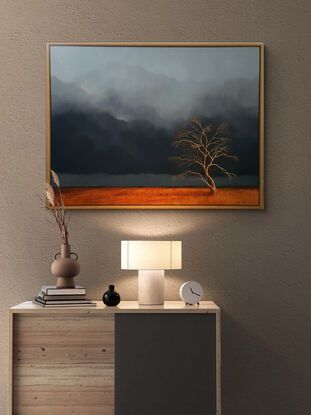 Australian landcape with  burnt orange grasses, deep blue grey cloudy sky and an old tree in the foreground