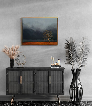 Australian landcape with  burnt orange grasses, deep blue grey cloudy sky and an old tree in the foreground