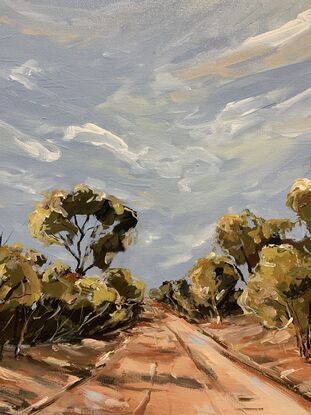 A dirt track weaves between gum trees with a peachy sky