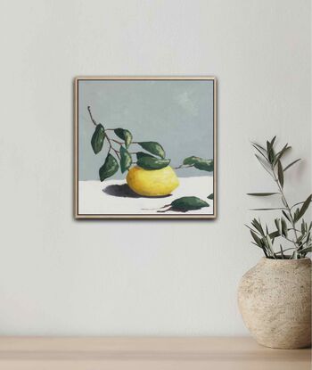 A lemon on a branch with leaves painted with subtle texture on a cream base and a blue grey background