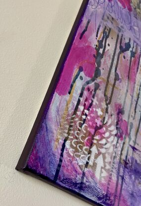 An image of a canvas full of dark hues of purple and navy with hints of magenta acrylic, covered in gold spray paint mixed with water