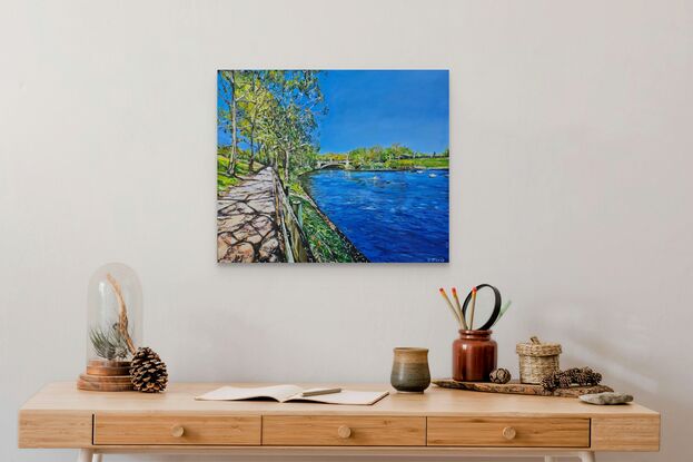 A medium landscape painting of the path beside the river Torrens. The river and the sky is a vivid blue, the grass and reeds are a bright green. There are gum trees to the left of the path. 