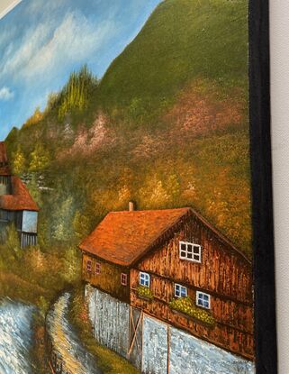 A river flows between the Castle and a house nestled in the Swiss Alps.