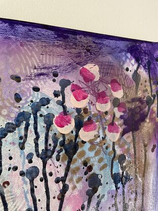 An image of a canvas full of dark hues of purple and navy with hints of magenta acrylic, covered in gold spray paint mixed with water