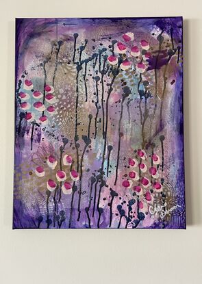 An image of a canvas full of dark hues of purple and navy with hints of magenta acrylic, covered in gold spray paint mixed with water