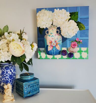 Striking white snowy hydrangeas in a tobacco leaf vase with plums on a tablecloth