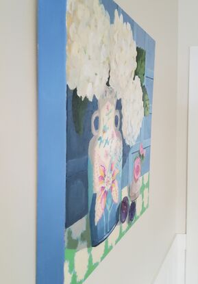 Striking white snowy hydrangeas in a tobacco leaf vase with plums on a tablecloth