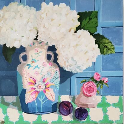 Striking white snowy hydrangeas in a tobacco leaf vase with plums on a tablecloth