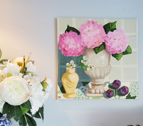 A Serene Still Life of 3 Pink Hydrangeas in a neutral toned terracotta Urn with 3 plums on patterned fabric.