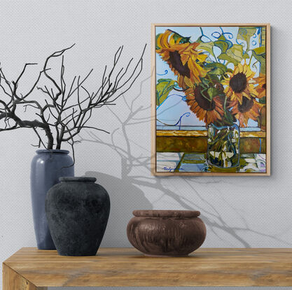 Sunflowers in glass vase on window ledge.