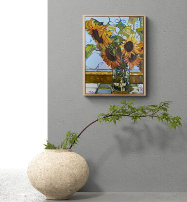 Sunflowers in glass vase on window ledge.