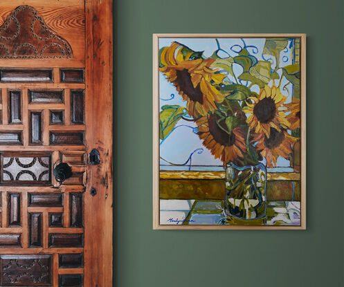 Sunflowers in glass vase on window ledge.