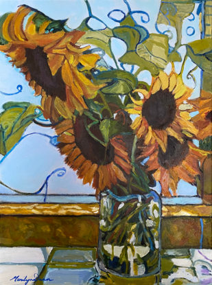 Sunflowers in glass vase on window ledge.