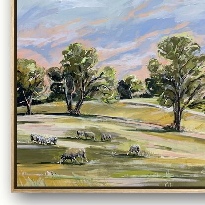 Rolling green hills scattered with grazing sheep. The sky is beginning to turn from pink to blue. Gum trees line the horizon.