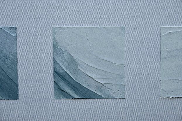 A grid of textured blue, white and grey squares, slightly extruding from the canvas, representing an ocean wave, set against a background of light blue/grey.