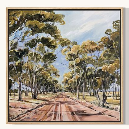 A dirt track runs between a large group of tall gum trees. A blue sky has whispers of clouds. 