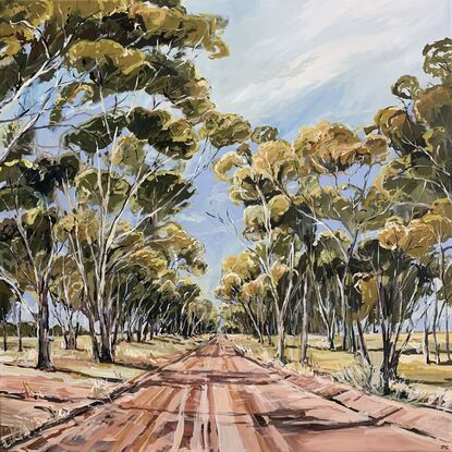 A dirt track runs between a large group of tall gum trees. A blue sky has whispers of clouds. 